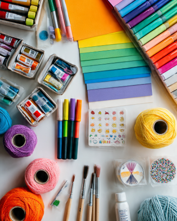 Essential craft tools for beginners with colorful paper, markers, yarn, brushes, and craft supplies.