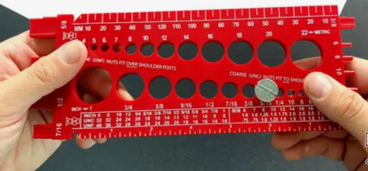 Red plastic screw and bolt sizing gauge tool with metric and inch measurements.