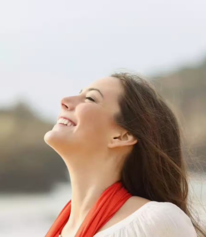 "A woman smiling outdoors with her head tilted back, demonstrating joy and happiness to answer why is beauty important in life."