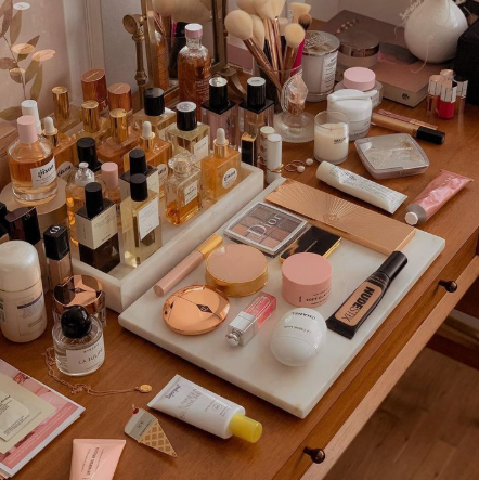 "An organized vanity table neatly arranged with various perfume bottles, makeup palettes, cosmetic products, brushes, and skincare items, showcasing the aesthetic appeal of personal care and why is beauty important in life."