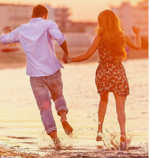 "A young couple holding hands and joyfully running through the shallow water of a beach at sunset, highlighting human connection and why is beauty important in life."