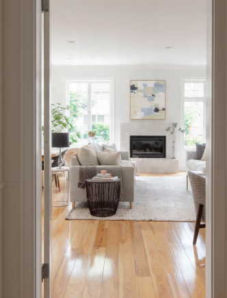 A warm, inviting view through a doorway into a beautifully styled living room that exemplifies principles from the 7 rules of decorating. featuring polished hardwood floors and a cozy fireplace centerpiece