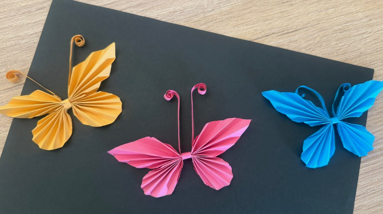 Three colorful origami butterflies arranged on a black background as part of easy paper crafts.