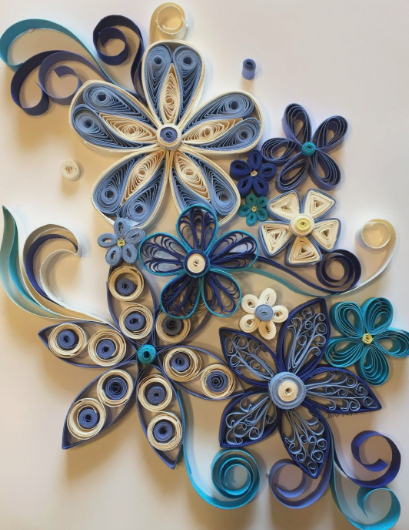 A creative paper quilling art piece featuring intricate blue, white, and purple flowers and swirls showcasing easy paper crafts.