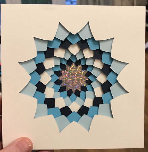 A multilayered shadow box design in shades of blue and white, featuring easy paper crafts with a sparkly center.
