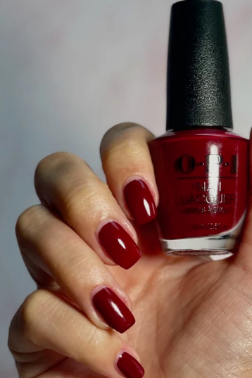 What nail colour is trending now displayed as a classic, glossy dark red lacquer on neatly squared nails holding an OPI nail polish bottle.