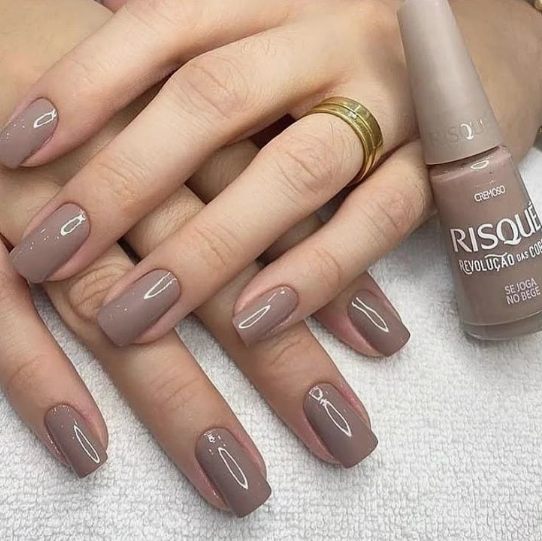 A close-up of beautifully manicured hands showcasing a sophisticated neutral taupe classy nail color next to its matching polish bottle, ideal for elegant everyday style inspiration on Humor Craze.