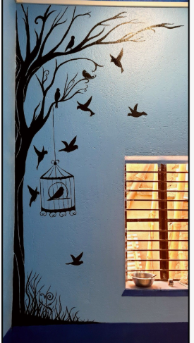 What Home Decor Items Are Trending in 2026? 15 Ideas to Refresh Your Home what home decor items are trending in 2026 highlighting a creative wall mural featuring a black silhouette tree with birds, a hanging birdcage, and a small window