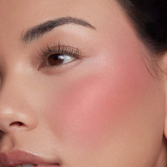 10 Makeup Trends for 2026: The Beauty Looks Everyone Will Want to Try A close-up shot of a model showcasing makeup trends 2026, highlighting a flawless complexion with flushed pink blush on the cheeks, defined brows, and natural lashes.