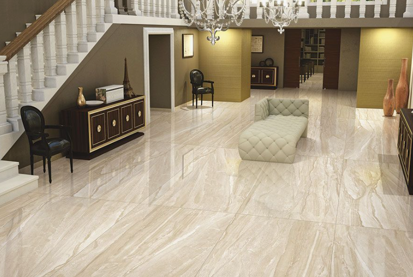 Expansive luxury foyer showcasing interior design trends 2026, featuring polished marble-effect porcelain floor tiles, a grand staircase with classical balusters, and a tufted chaise lounge.