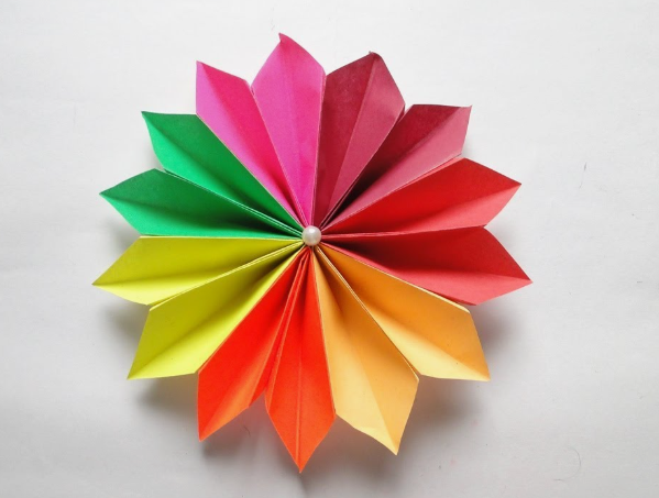 15 Easy DIY Paper Flowers for Kids: Fun Crafts for Toddlers, Preschoolers & Older Children A colorful, symmetrical paper craft flower made of folded segments in a rainbow of colors (red, orange, yellow, green, pink) with a pearl center, an easy paper flower for kids to make.