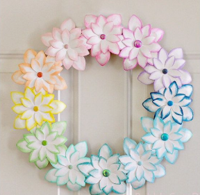 15 Easy DIY Paper Flowers for Kids: Fun Crafts for Toddlers, Preschoolers & Older Children A decorative wall wreath made of layered paper flowers arranged in a rainbow color gradient, featuring gems at the center of each blossom as easy paper flowers for kids.