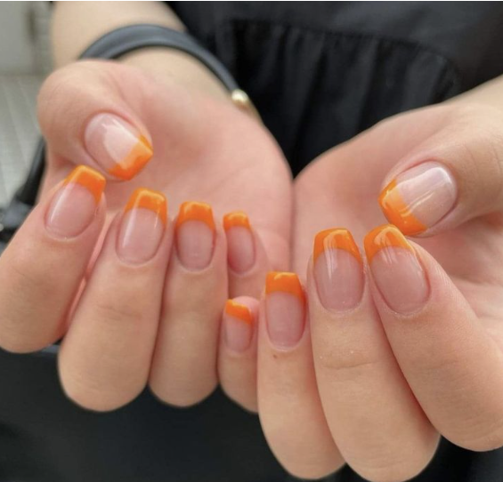 25 Short Fall Nail Ideas for 2026: Chic, Simple & Trendy Designs Short fall nail ideas 2026 showcasing short, squared nails styled with vibrant orange French tips over a neutral sheer base.