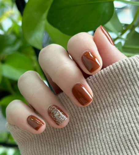 25 Short Fall Nail Ideas for 2026: Chic, Simple & Trendy Designs Short fall nail ideas 2026 showcasing short, squared nails finished in a glossy caramel-brown polish with a shimmering gold glitter accent nail.