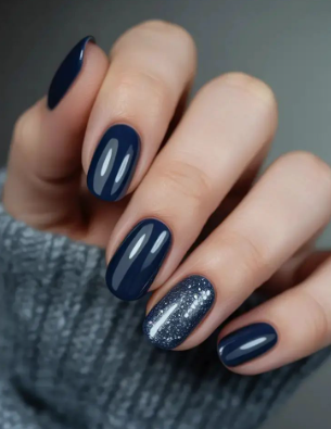 25 Short Fall Nail Ideas for 2026: Chic, Simple & Trendy Designs Short fall nail ideas 2026 showcasing short, rounded nails finished in a glossy dark navy blue polish with a sparkling silver glitter accent nail.
