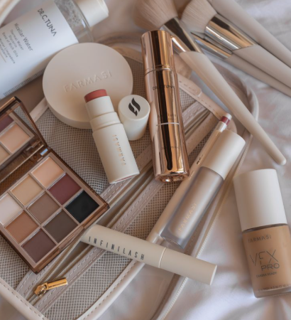 20 Types of Makeup and Their Uses: A Complete Beginner’s Guide Image Alt Text: Overhead flatlay of assorted cosmetic products including a makeup bag, brushes, palette, and foundation for types of makeup and their uses.
