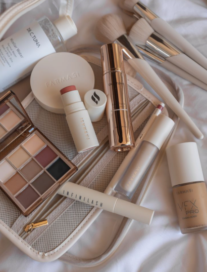 Image Alt Text: Overhead flatlay of assorted cosmetic products including a makeup bag, brushes, palette, and foundation for types of makeup and their uses.