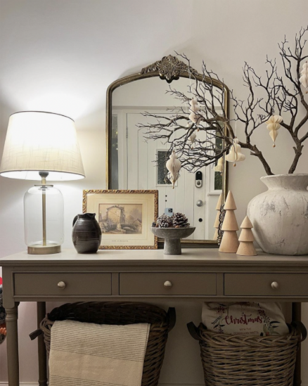 An ornate, dark-framed arched mirror reflecting the room and framing the decorative branch display as part of creative Halloween decor ideas for indoor spaces.