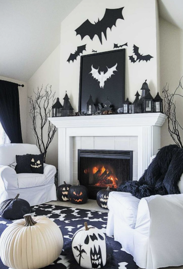 A bright white fireplace mantel lined with miniature black lantern-style houses, reflecting spooky Halloween decor ideas for indoor spaces.
