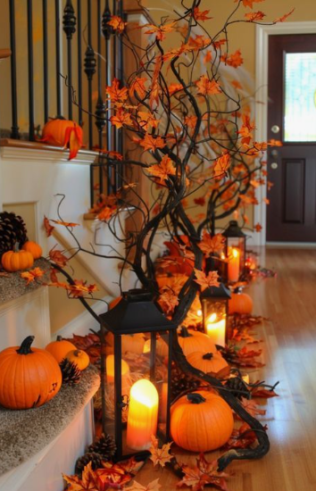 A vibrant hallway and staircase display featuring tall bare branches adorned with glowing orange fall leaves, creating stunning Halloween decor ideas for indoor spaces.