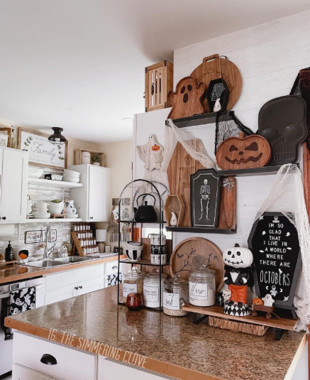 Open kitchen shelves layered with spooky wooden cutting boards, ghost plaques, and pumpkin shapes, creating stunning Halloween decor ideas for indoor spaces.