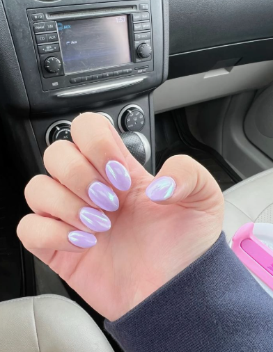 18 Back-to-School Nail Designs for a Fresh Start This School Year Close-up of glossy back-to-school nail designs featuring short, rounded nails coated in a shimmering pastel lavender chrome finish.