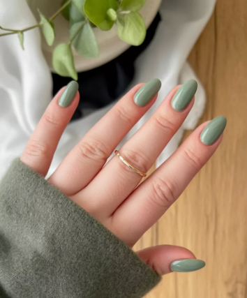 18 Back-to-School Nail Designs for a Fresh Start This School Year Close-up of elegant back-to-school nail designs featuring smooth, glossy sage green almond-shaped nails paired with a simple gold ring.