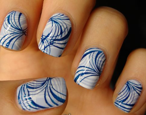 18 Back-to-School Nail Designs for a Fresh Start This School Year Close-up of stylish back-to-school nail designs featuring short, rounded nails with a light blue and white swirled marble background overlaid with intricate dark blue fan-like line art patterns.