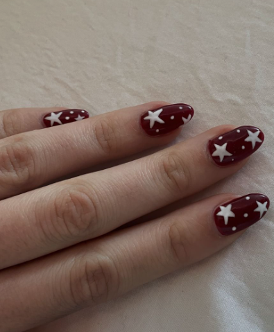 18 Back-to-School Nail Designs for a Fresh Start This School Year Close-up of stylish back-to-school nail designs featuring short, rounded nails with a light blue and white swirled marble background overlaid with intricate dark blue fan-like line art patterns.