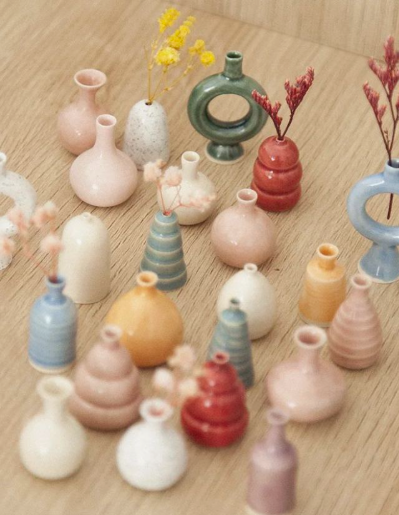 A collection of creative air dry clay ideas featuring various miniature pastel vases and pots arranged on a wooden surface.