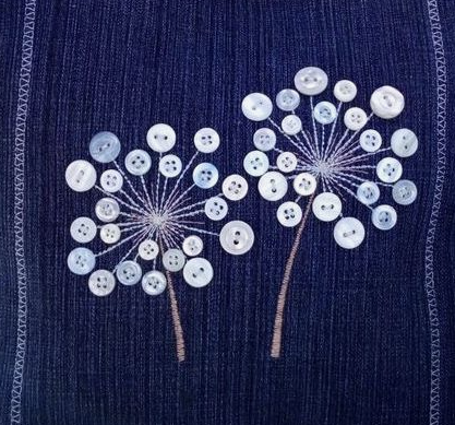 30 Creative DIY Button Crafts to Turn Spare Buttons Into Beautiful Decor A dark denim fabric embellished with embroidered dandelion seed heads featuring delicate white and translucent buttons at the tips, showcasing DIY button crafts.