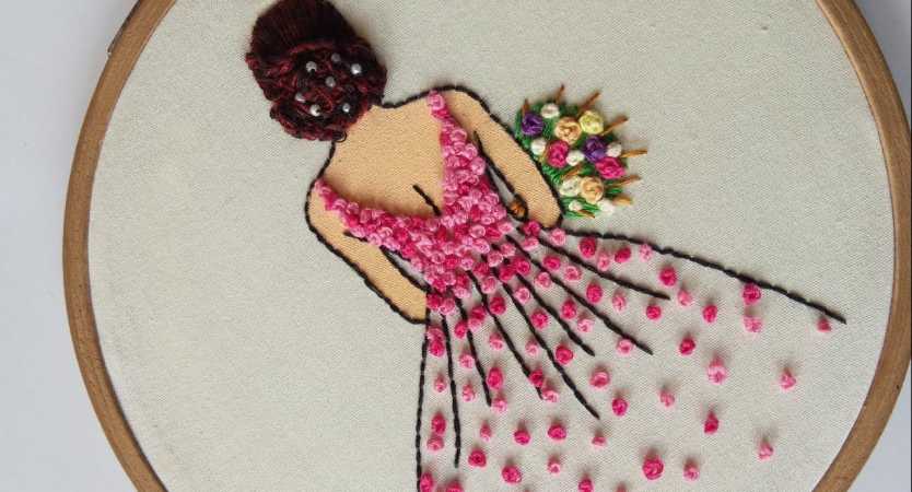 DIY crafts to sell: embroidery hoop art featuring a woman from behind wearing a stunning pink floral dress and holding a bouquet.