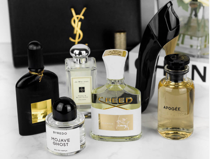 An assortment of luxury perfume bottles from brands like Tom Ford, Byredo, Jo Malone, Creed, Louis Vuitton, and Carolina Herrera arranged on a tabletop, showcasing beauty products worth buying.