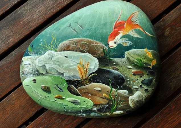 25 Crafts for People Who Aren't Artistic That Are Easy to Try A large, smooth garden stone meticulously hand-painted with an underwater aquatic scene featuring a vibrant goldfish, river rocks, and aquatic plants, showcasing stunning home decor ideas without buying anything.