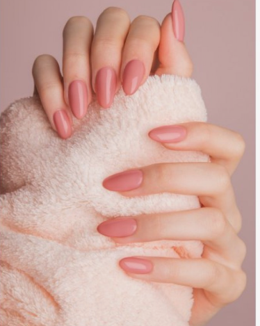 Hands holding a soft pink fluffy blanket, showcasing polished almond-shaped dusty rose nails as graceful nail colors that make hands look younger.