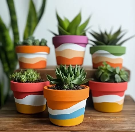 A collection of colorful hand-painted terracotta pots filled with succulents, showcasing one of 25 easy DIY home decor crafts for plant lovers."