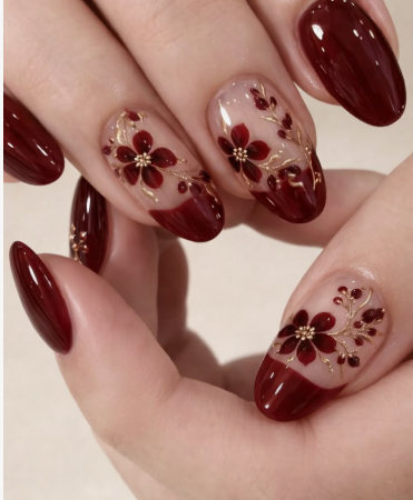 Elegant oval-shaped burgundy nail designs featuring a mix of solid deep dark red nails, shimmering gold foil accents, and delicate painted floral nail art on a nude base.