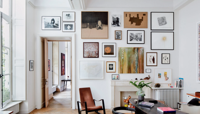 Vintage Modern Home Decor Ideas: 15 Ways to Mix Old and New "A bright, modern living room showcasing Vintage Modern Home Decor Ideas, featuring an extensive gallery wall of contemporary and vintage framed art prints, a minimalist fireplace, a brown leather armchair, and high ceilings."