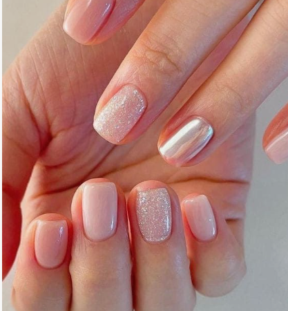 Close-up of nail designs for short nail beds featuring a mix of glossy neutral pink nails, a glitter accent nail, and a reflective chrome accent nail on short, squared-rounded nails.