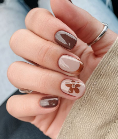 Close-up of nail designs for short nail beds showcasing a mix of solid dark brown polish, a brown French tip accent, and a retro brown flower design on short, squared-rounded nails.