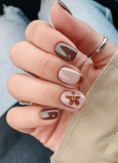 Close-up of nail designs for short nail beds showcasing a mix of solid dark brown polish, a brown French tip accent, and a retro brown flower design on short, squared-rounded nails.