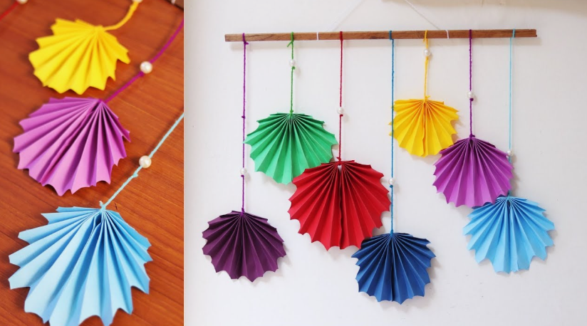 "A colorful handmade accordion-folded paper wall hanging with hanging fan shapes, featured as one of 25 easy DIY home decor crafts."