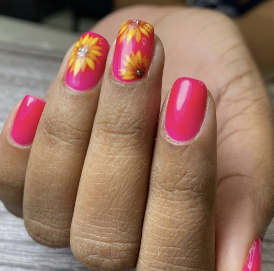 24 Sunflower Nail Ideas for a Bright, Cheerful Manicure sunflower nail ideas featuring vibrant hot pink nails with accent nails painted with bright yellow sunflowers.