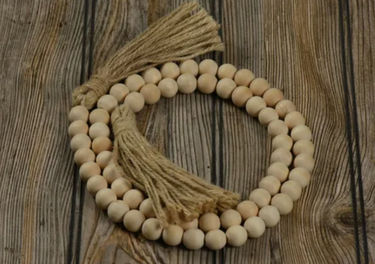 "Natural wooden bead garland styled with rustic jute tassels, featured as part of 25 easy DIY home decor crafts for tabletop accents."