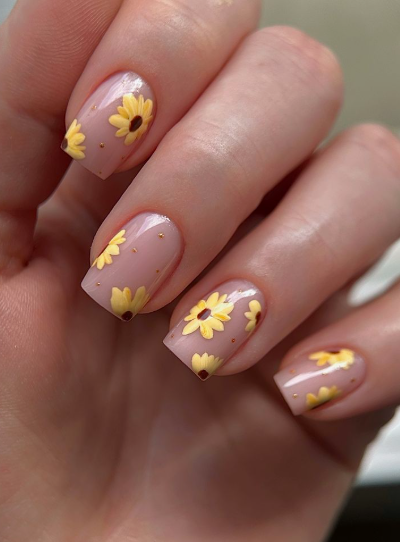24 Sunflower Nail Ideas for a Bright, Cheerful Manicure sunflower nail ideas featuring short, square nails with a sheer nude base decorated with scattered small yellow sunflowers and tiny gold dot accents.