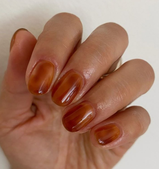 A hand showcasing short, glossy tortoise shell pattern nails, styled for fall nail ideas 2026.