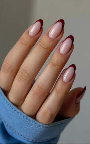 Hands showcasing short, squoval nails with a mix of deep burgundy French tips and solid burgundy polish, styled for fall nail ideas 2026.  