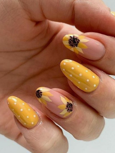 24 Sunflower Nail Ideas for a Bright, Cheerful Manicure sunflower nail ideas featuring almond-shaped nails with a playful mix of solid yellow polka-dot patterns and accent nails showcasing hand-painted sunflowers on a nude base.
