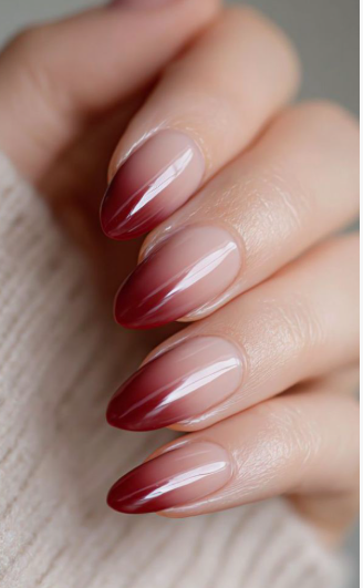A hand showcasing long, almond-shaped burgundy ombre french nails, styled for fall nail ideas 2026.