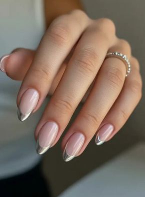 A hand with long, almond-shaped nails featuring metallic silver chrome French tips, styled for fall nail ideas 2026.